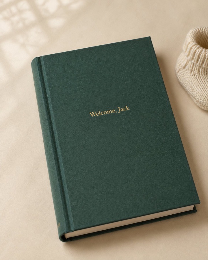 A finished Chorus book for a new baby, on a table beside a knitted bootie